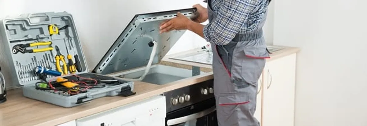 Cooktop repair technician lifting a built-in stovetop for service in Pembroke Pines, FL